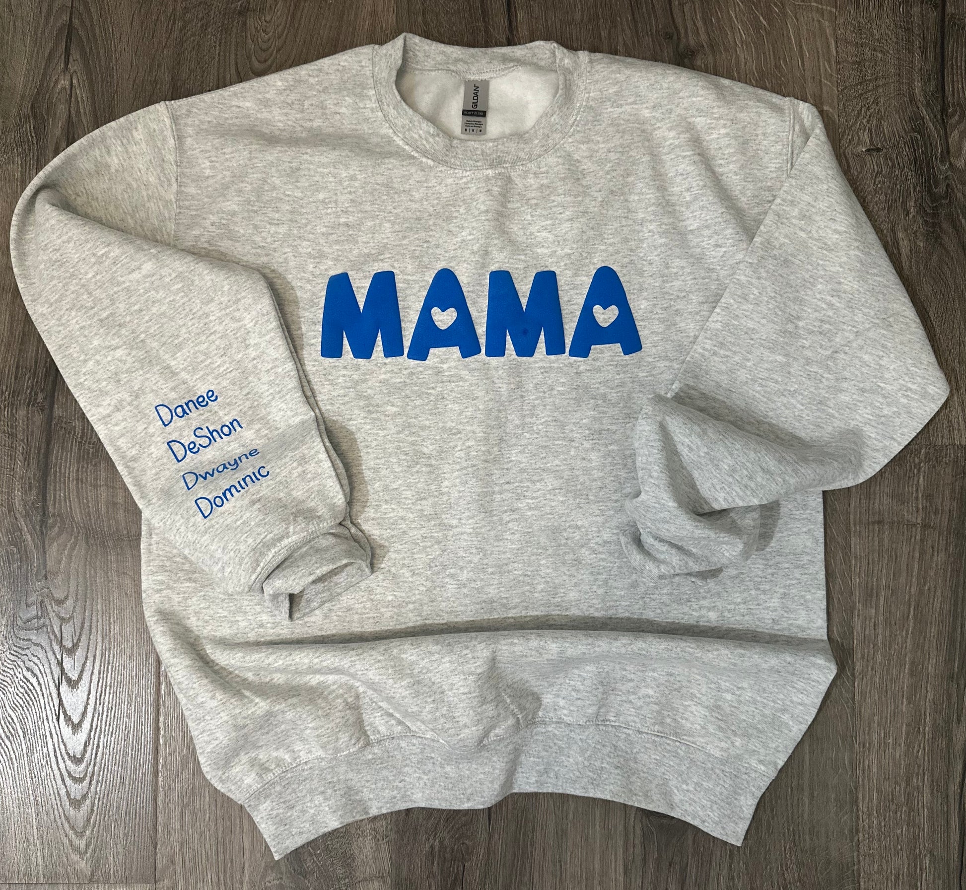 Light sweatshirt with the word MAMA in the middle. The A's have a heart in the center. One of the sleeves has 4 names. The MAMA and names are in neon blue